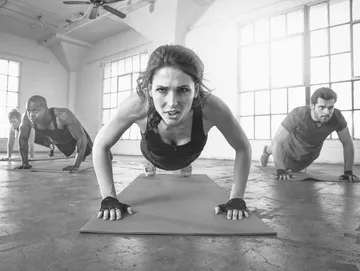 Group of people doing push-ups on exercise mats in a gym